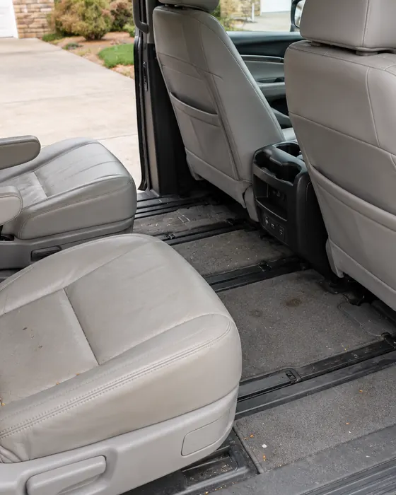 Second row of a family minivan with crumbs on the seat and dirt in the carpet, before the Reset